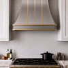 Faceted Curved Custom Stainless Steel Range Hood with Matte Brass Straps and Rivets
