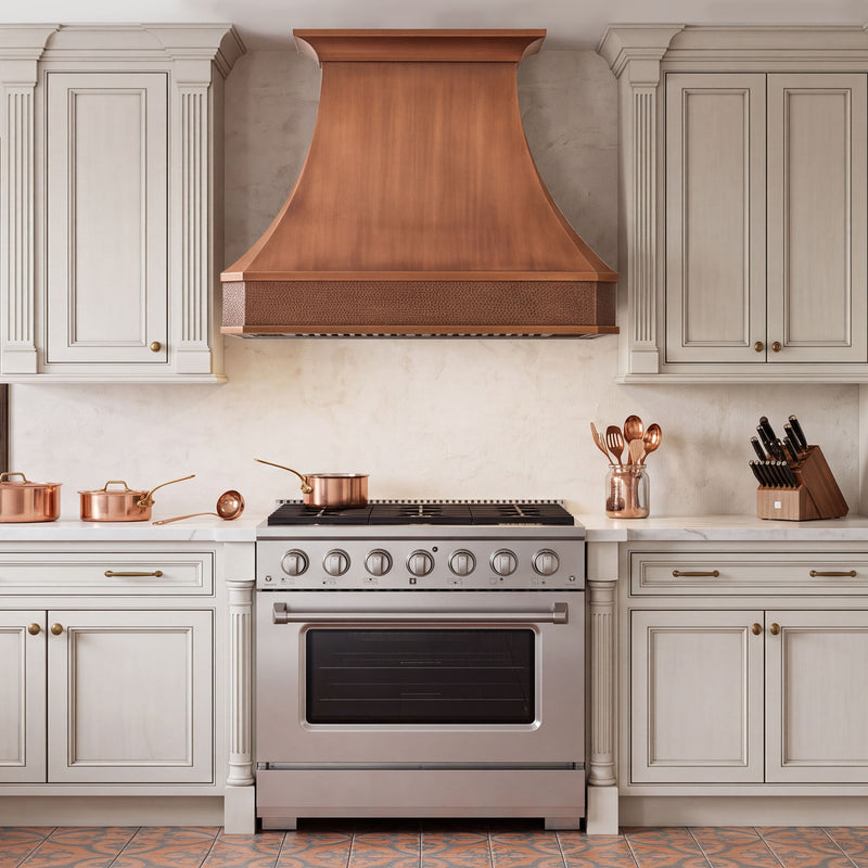 Traditional kitchen with handcrafted custom copper curve shape range hood and hammered apron detail